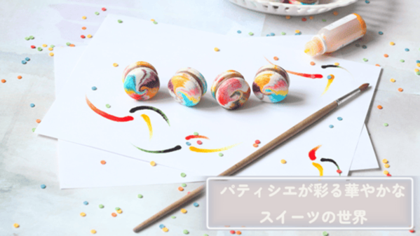 右下に”パティシエが彩る華やかなスイーツの世界”と記載。白い机の上で画用紙と丸いヨーヨーをカラフルに色付けしている画像